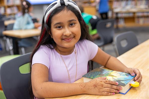 girl smiling at table with book